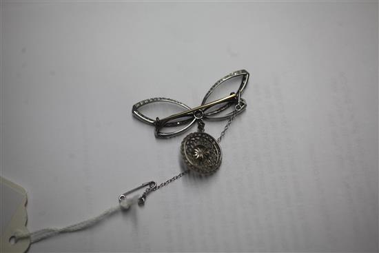 A Belle Epoque platinum and gold, diamond and split pearl set bow brooch with openwork target drop, width 2in.